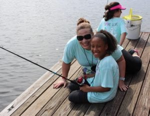 Girl camper fishing on a dock.